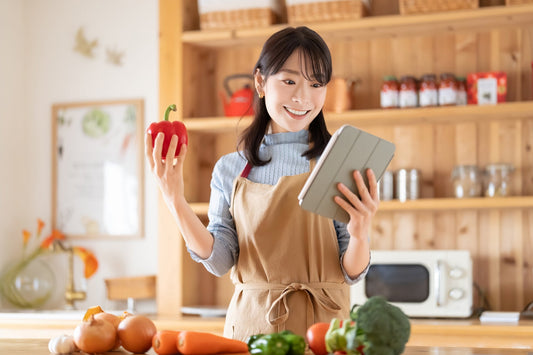 アプリを見ながら料理をする笑顔の女性
