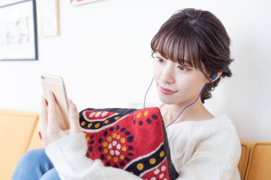 イヤホンをしながらスマホを見る女性